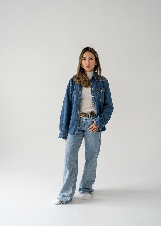 Person wearing a vintage medium wash denim button up long sleeve shirt and jeans on a white background