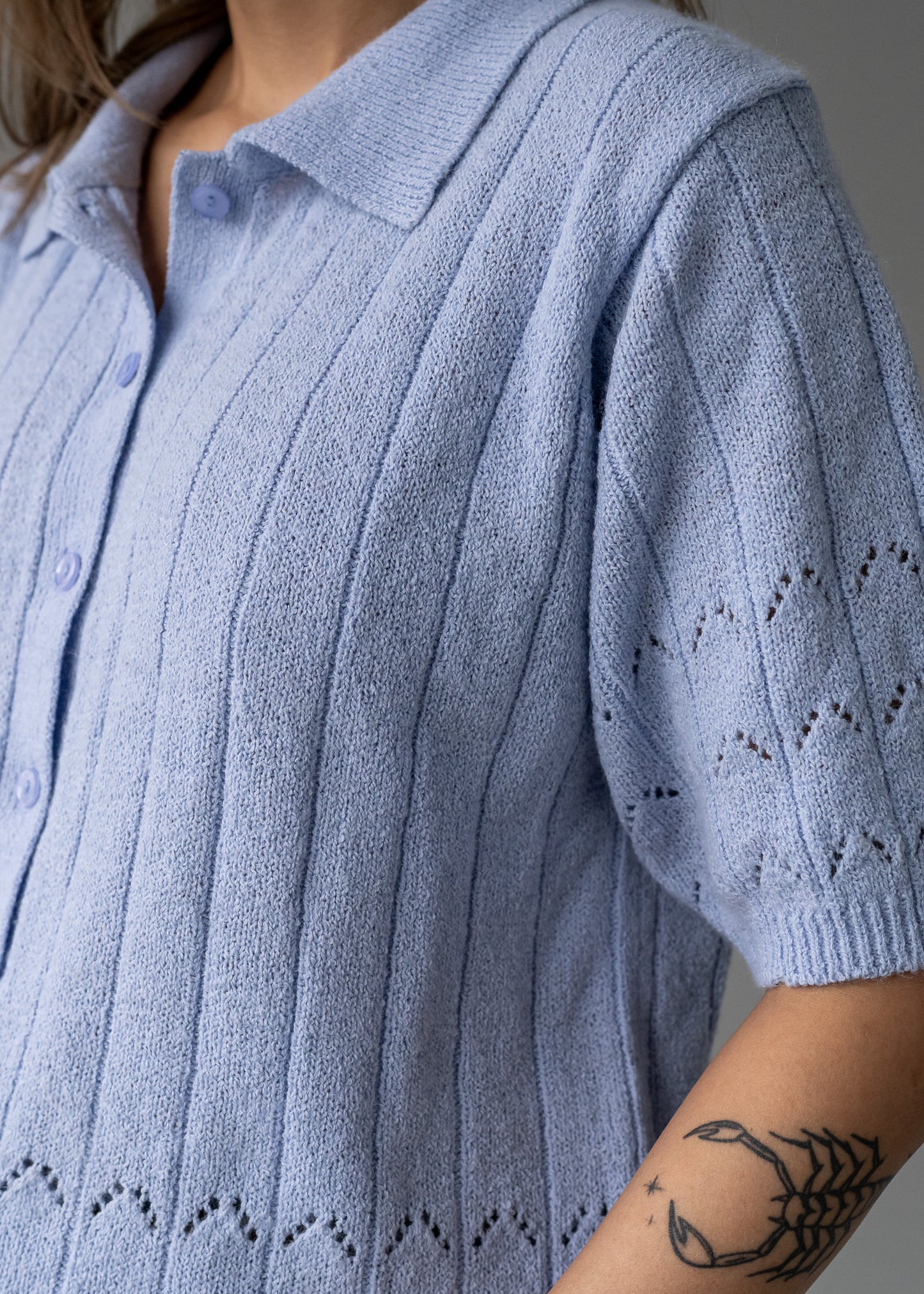 Light lavender vintage knitted cardigan with a patterned sleeve on a neutral background