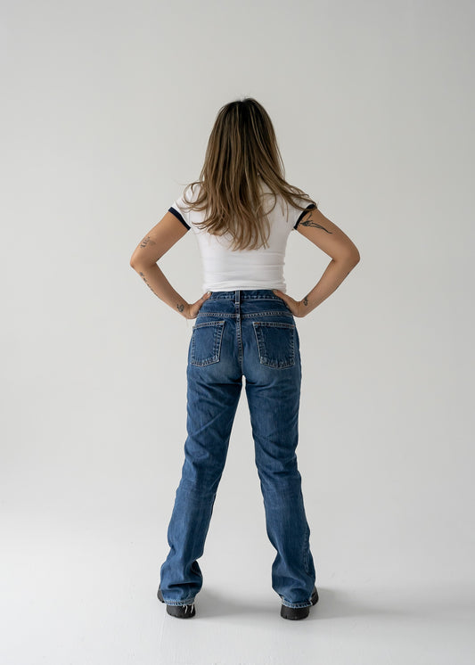 Person wearing vintage medium wash, mid-rise straight boot cut jeans and a white top from the back.
