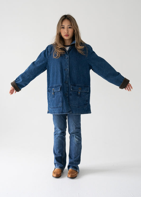 Person wearing a vintage blue wash denim quilted lining jean jacket with a rounded collar, long sleeves, and flap pockets and jeans on a white background