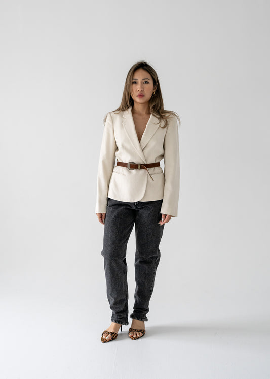 Woman standing against a white background wearing straight leg vintage black medium wash high rise jeans and cream linen blazer