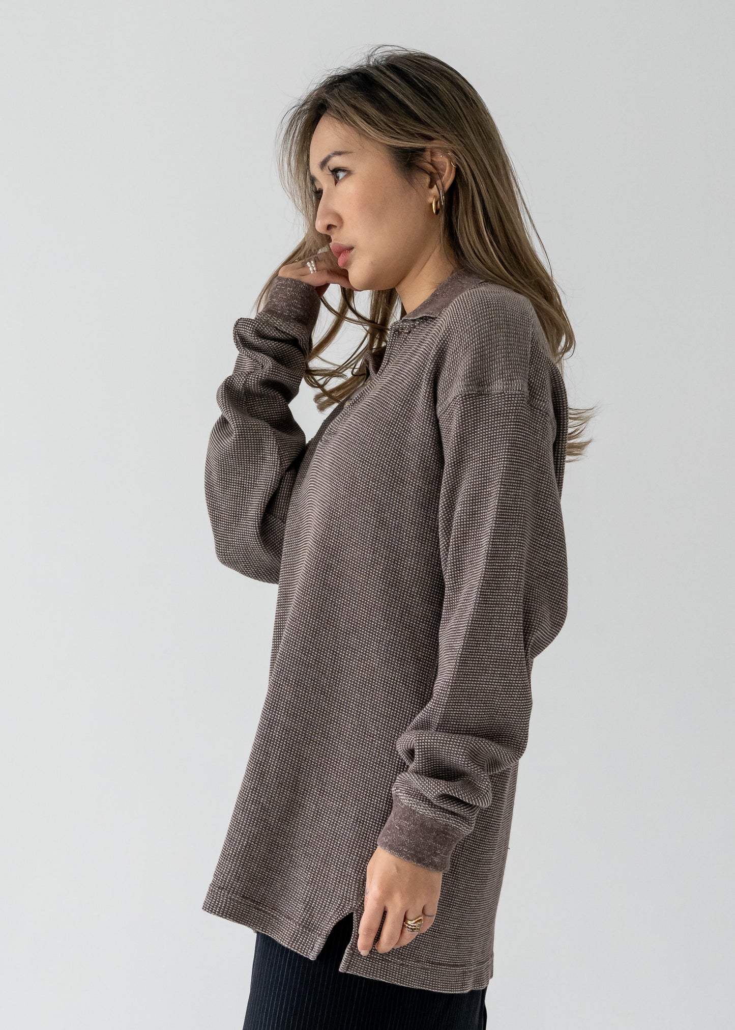 A woman wearing a vintage long sleeve, brown collared pullover waffle knit shirt with a 1/4 button up front.