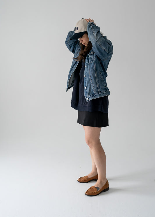 Person wearing a vintage navy and taupe Oscar de la Renta long sleeve pullover shirt and vintage denim jacket on a plain background
