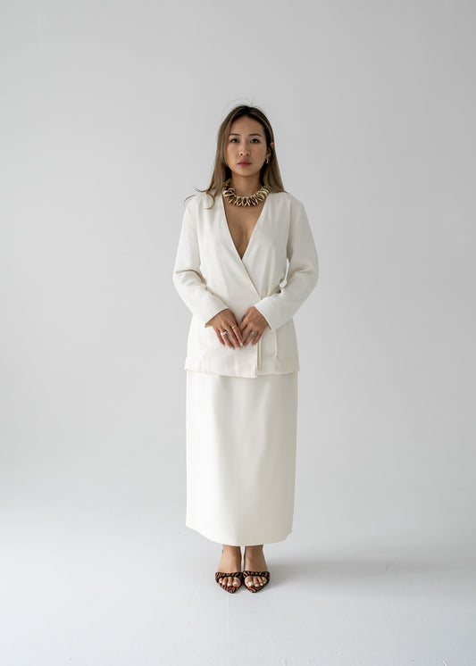 A woman modeling a white slinky rayon 3/4 sleeve tie-back blouse with a deep V-neck and a cinched waist at the center back.