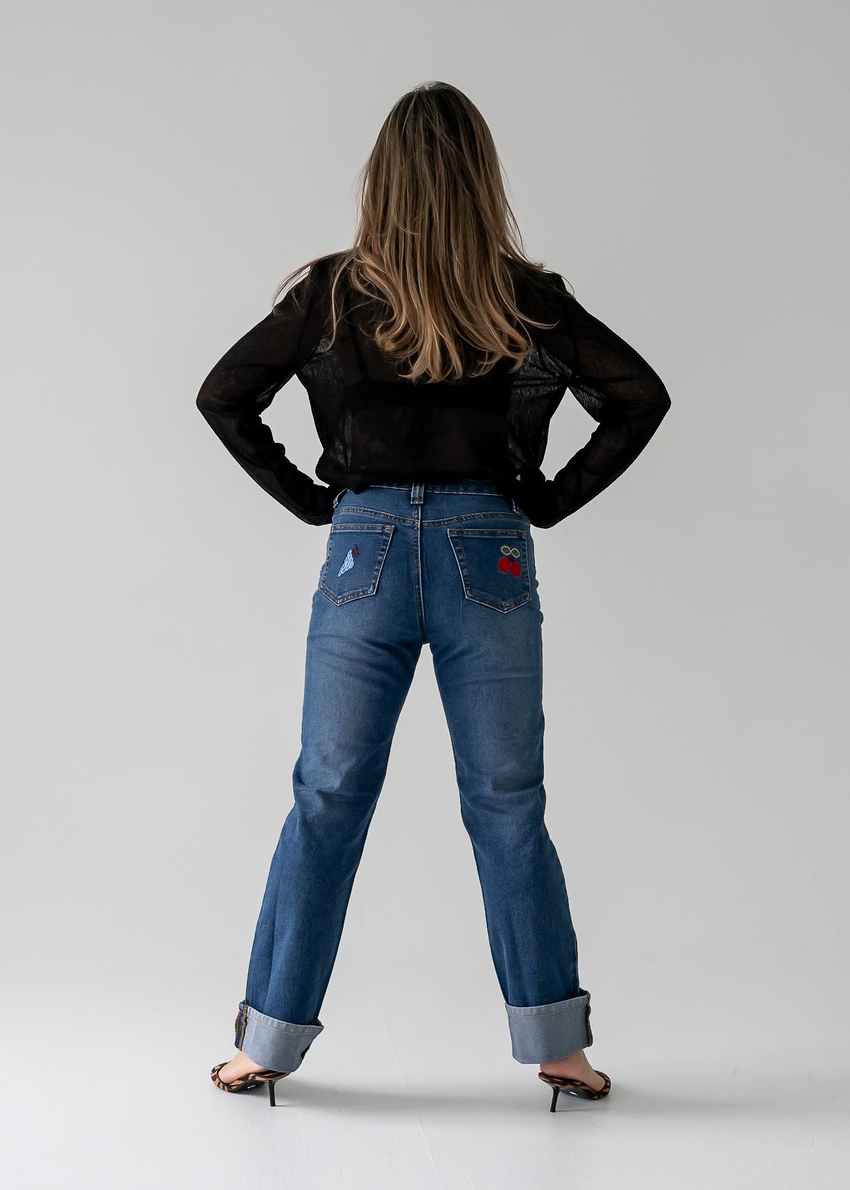 Person wearing vintage blue jeans and a sheer black top from the back.