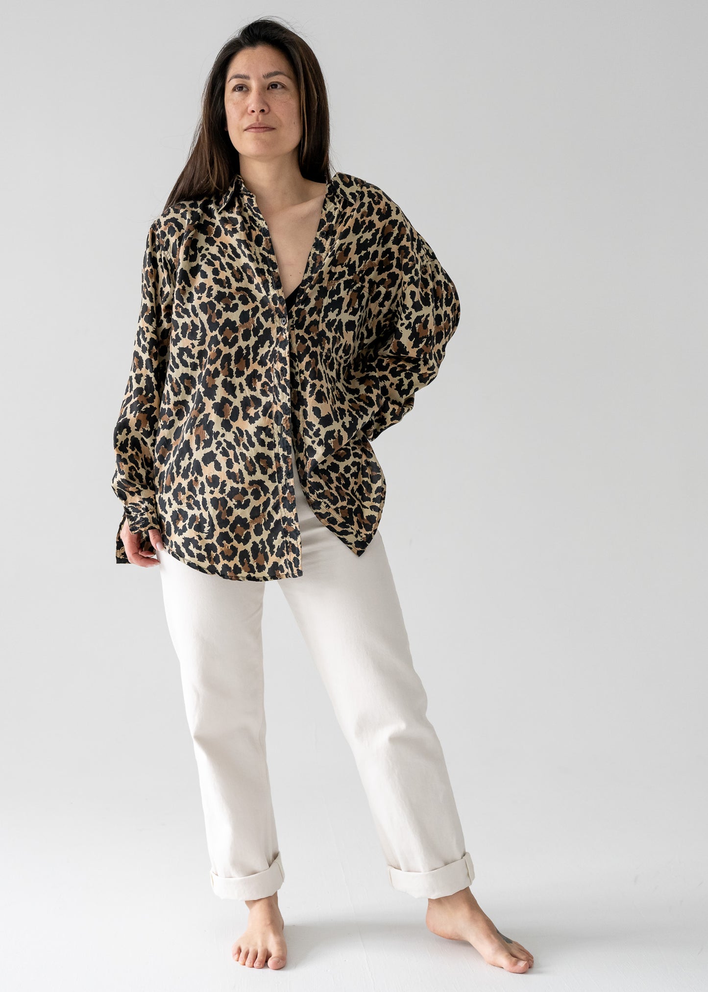 Person wearing a vintage silk leopard animal print long sleeve button up blouse and white pants in a studio setting.