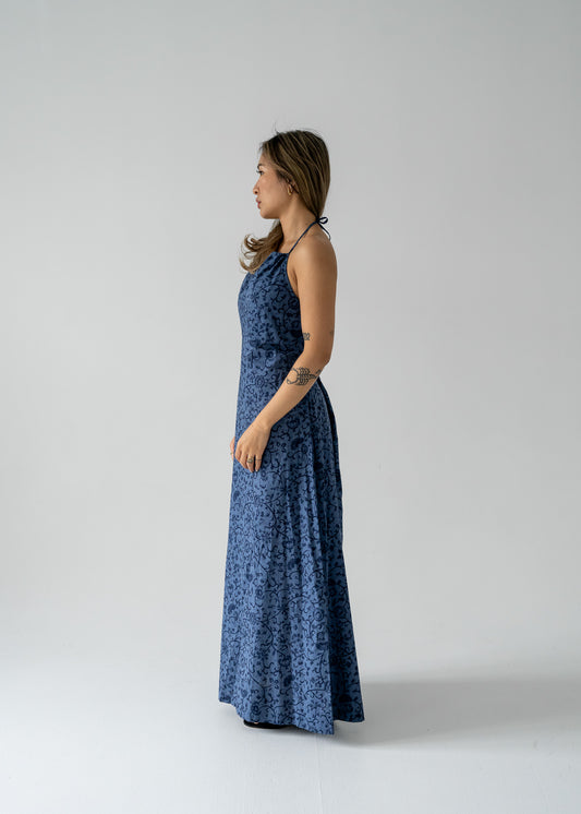 Woman wearing a vintage slate blue floral lightweight cotton drawstring halter maxi sundress on a plain background