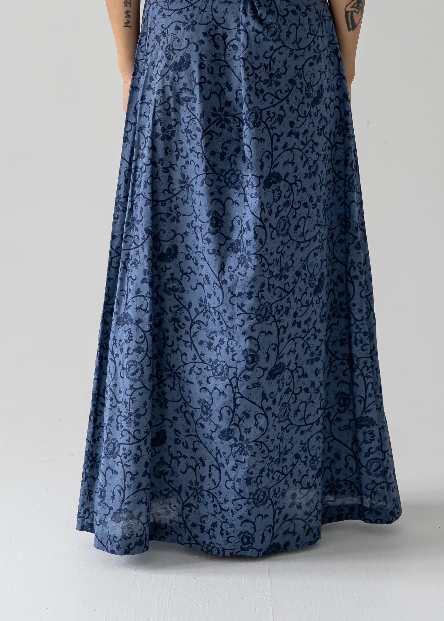 The image shows the back view of a vintage slate blue floral lightweight cotton drawstring halter maxi sundress, with a focus on the dress's line and the dark blue floral pattern against the slate blue base.