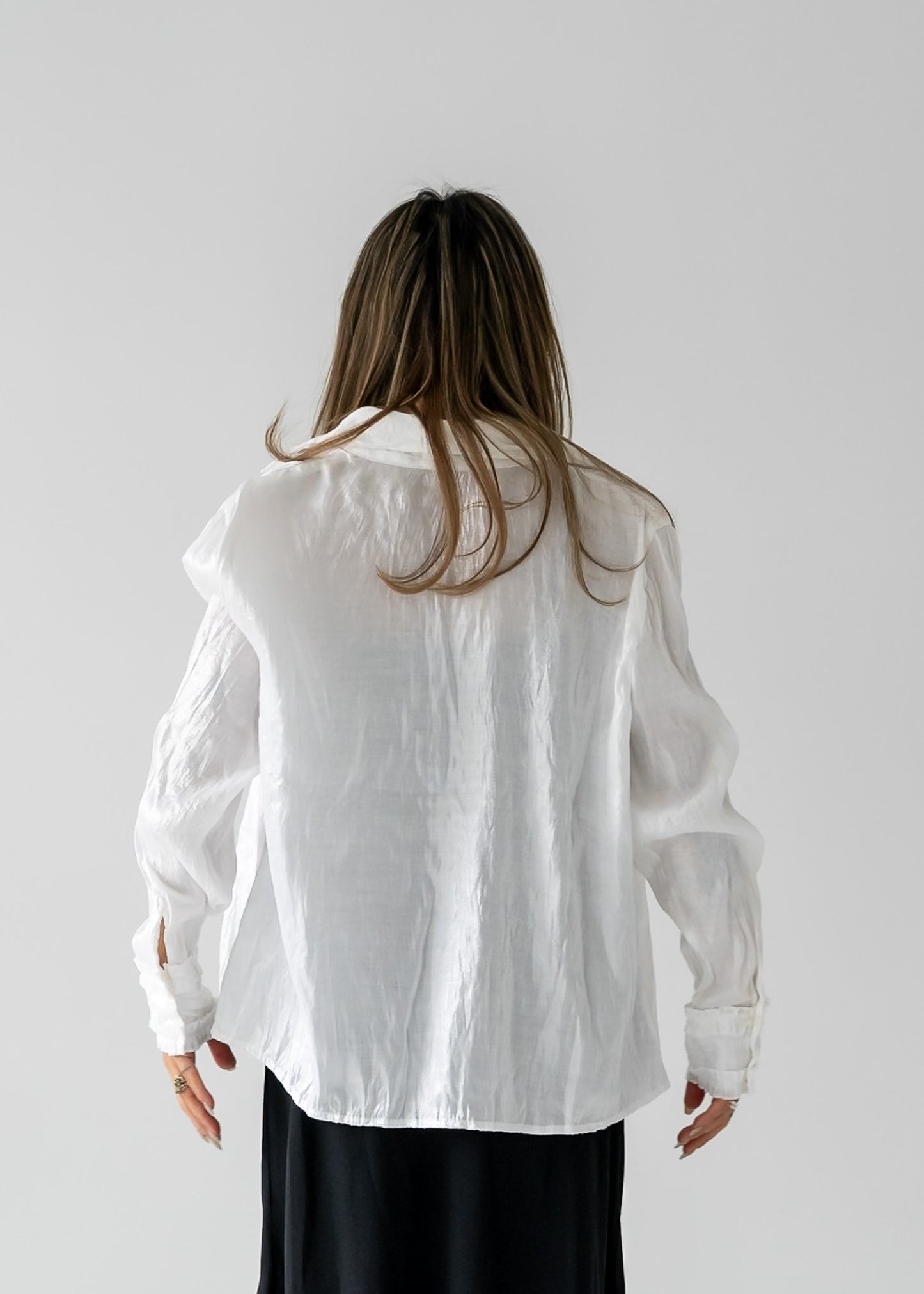 person wearing a vintage white, long-sleeved, button-up blouse with a mini ruffle at the wrist over a black dress