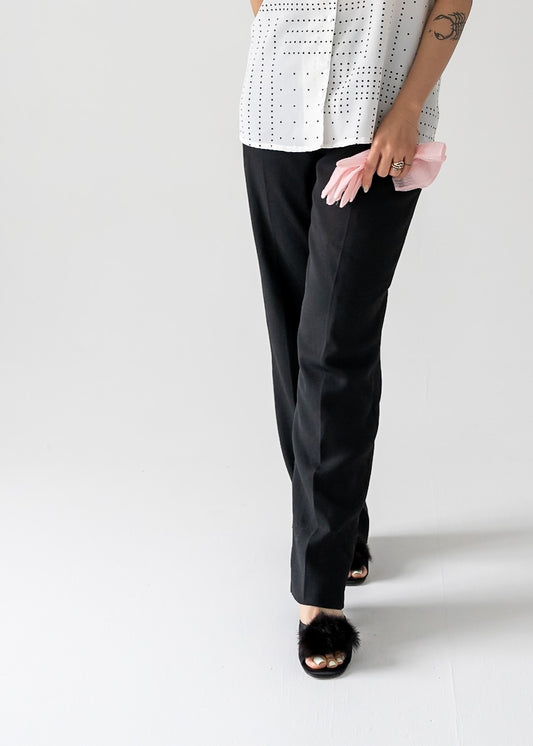 Person wearing black pants and a white top on a plain background