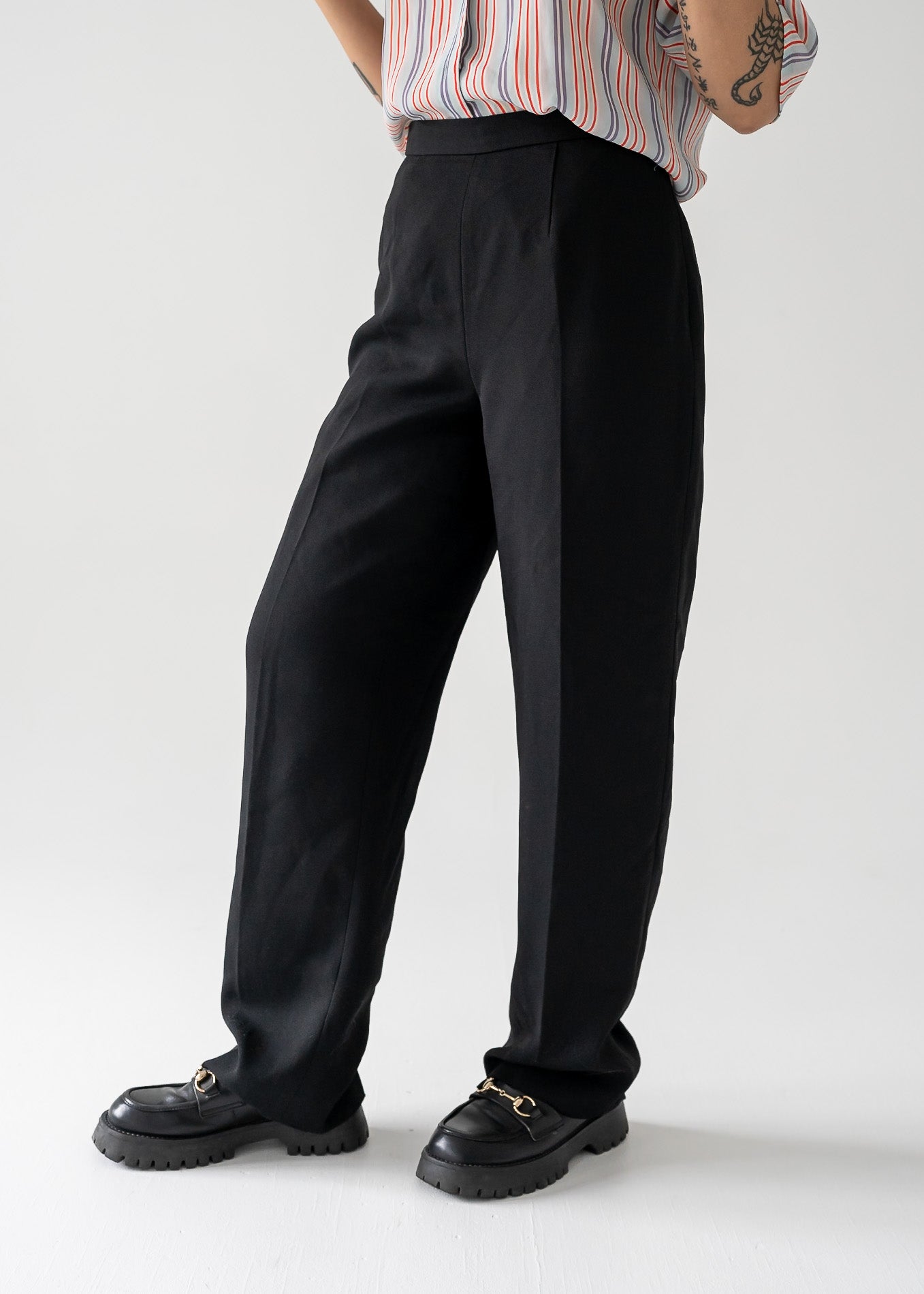 Person wearing vintage black pants and black shoes on a white background