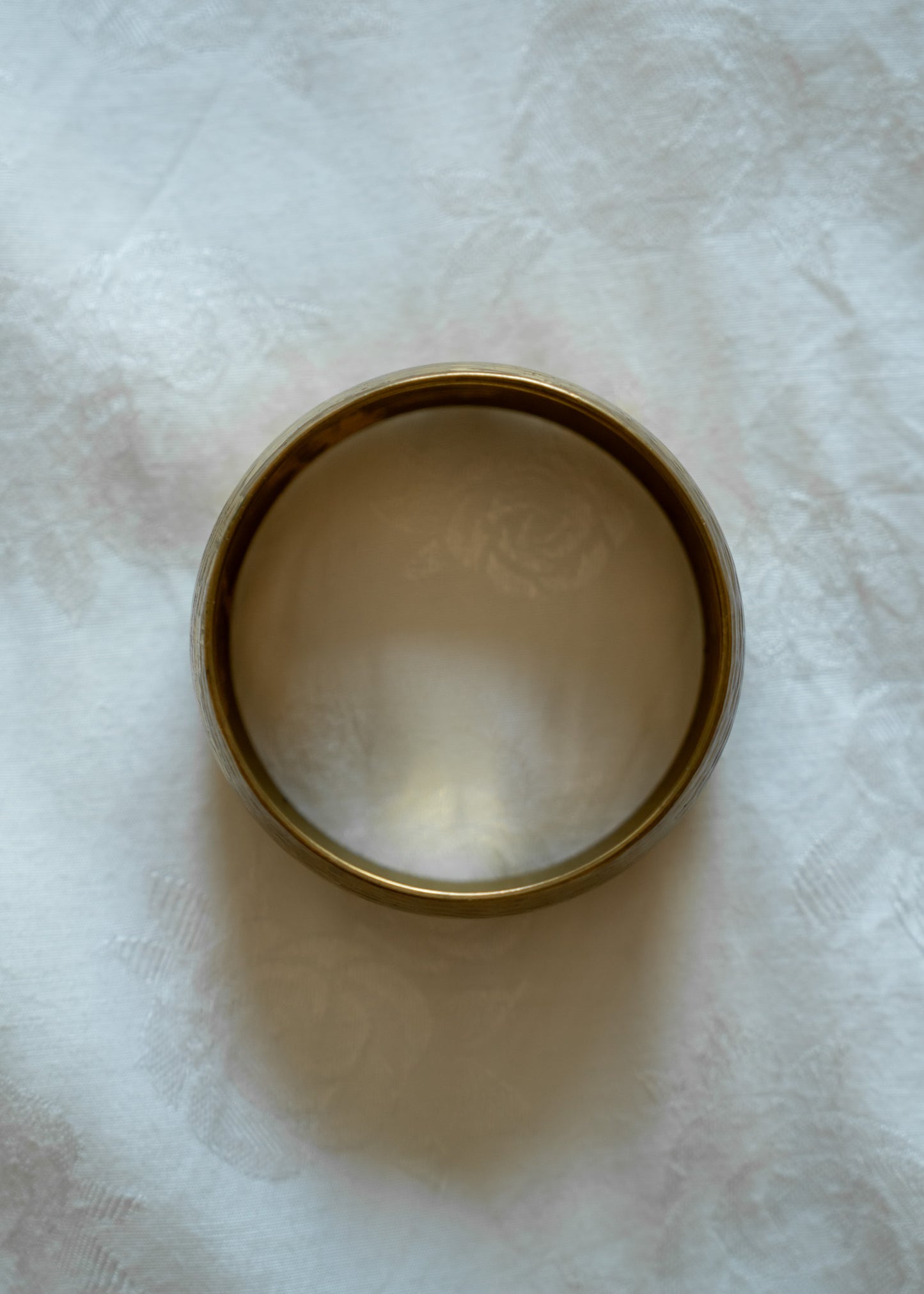 Etched brass bangle on a white fabric background