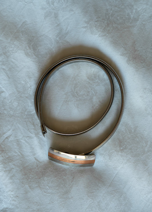 Silver metal belt on a textured white surface