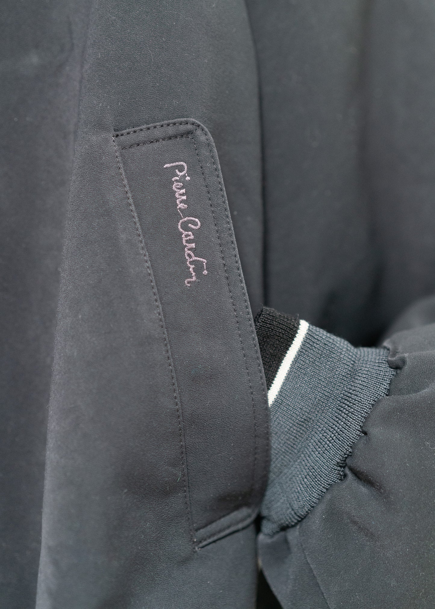 Close-up of a vintage navy jacket with a Pierre Cardin brand logo on the pocket