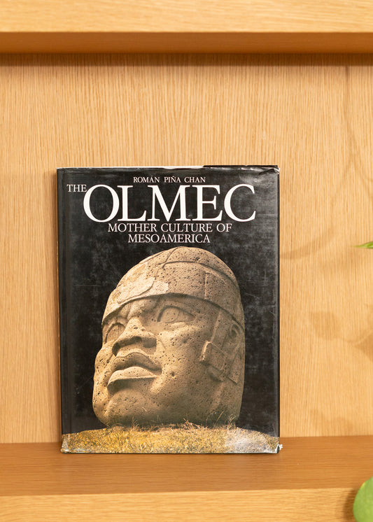 Vintage book titled 'The Olmec: Mother Culture of Mesoamerica' on a wooden shelf