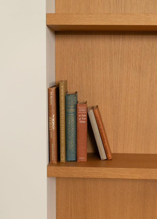 Wooden bookshelf with vintage books against a beige wall