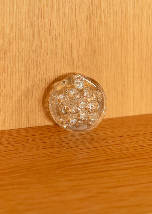 a vintage round, clear glass flower frog against a wooden background