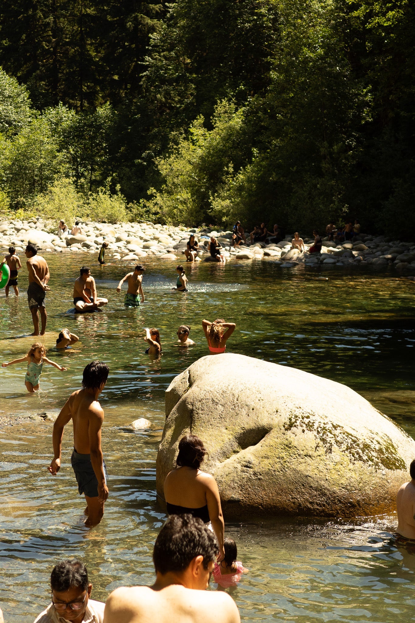 A Summer scene of people of all ages enjoying an afternoon swim in a river