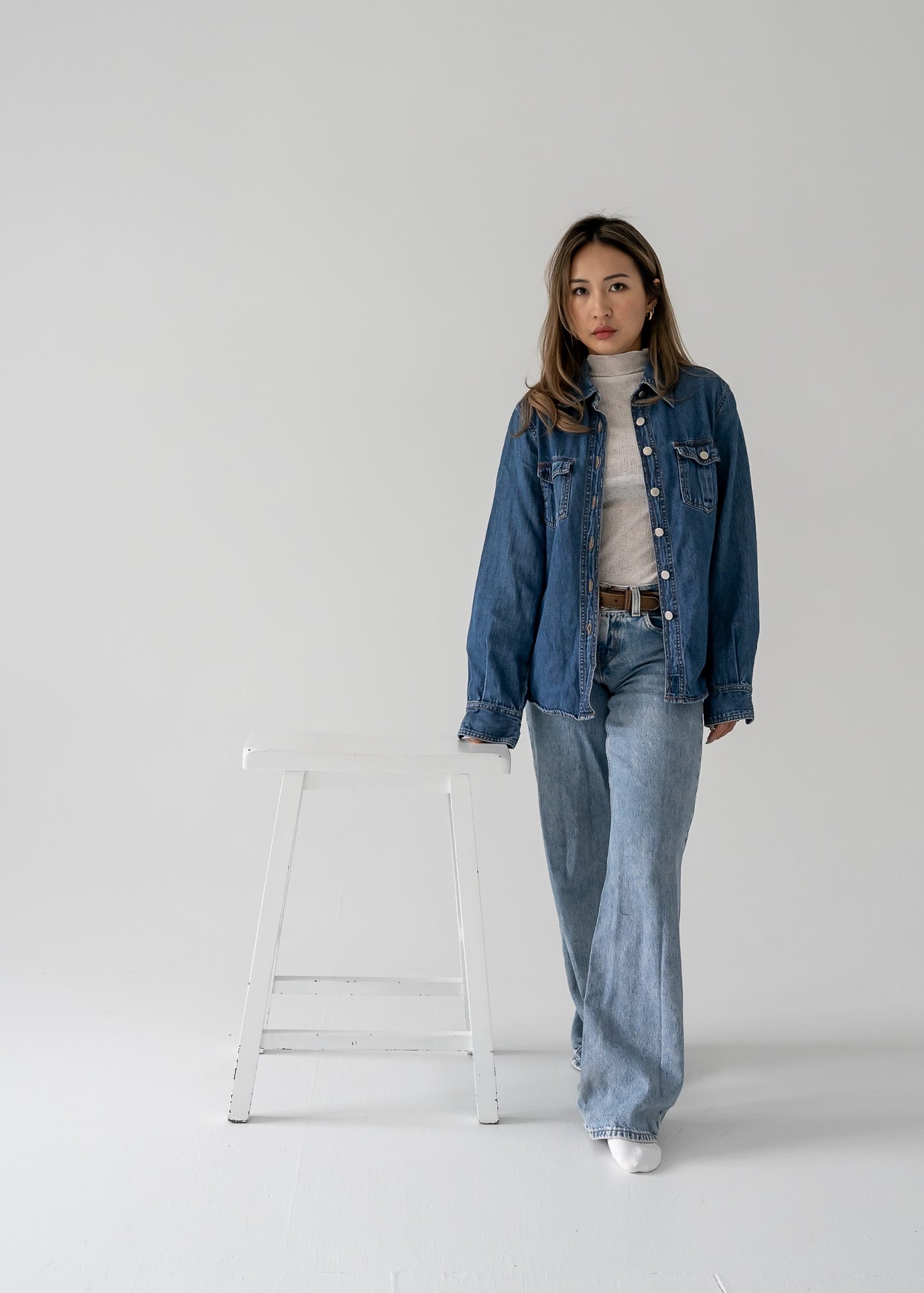 Person wearing a vintage medium wash denim button up long sleeve shirt and jeans on a white background.