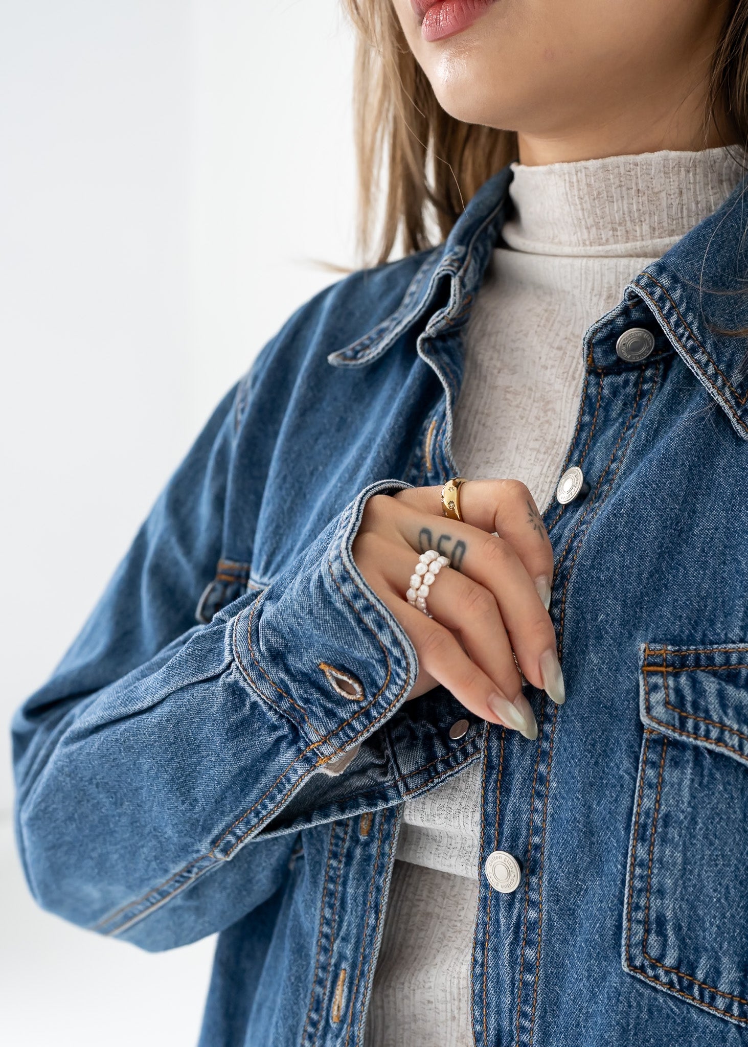 Person wearing a vintage medium wash denim button up long sleeve shirt on a white background