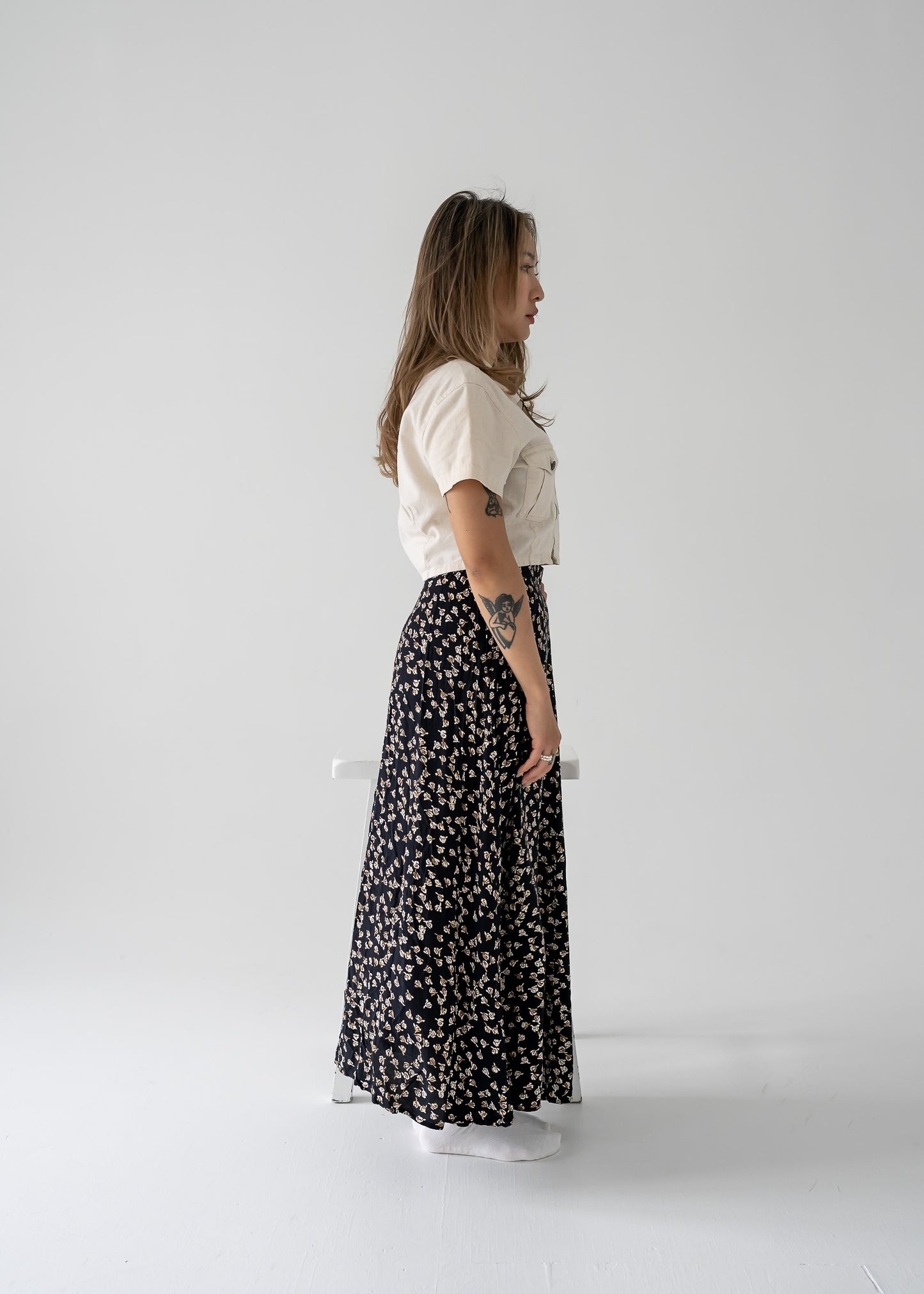Woman in a white top and vintage black floral skirt standing against a white background