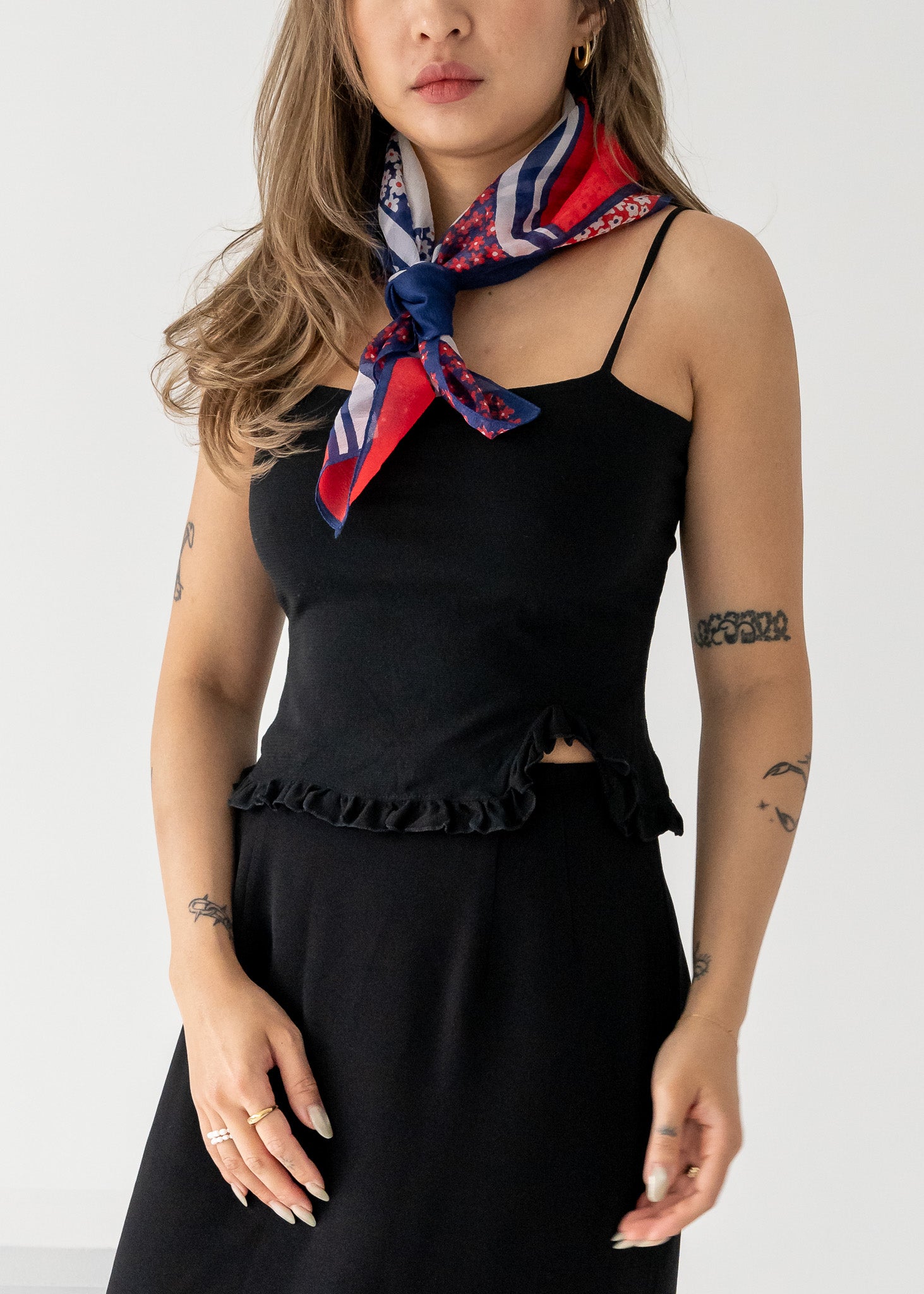 woman wearing a black outfit and a blue, white and red floral scarf around her neck.