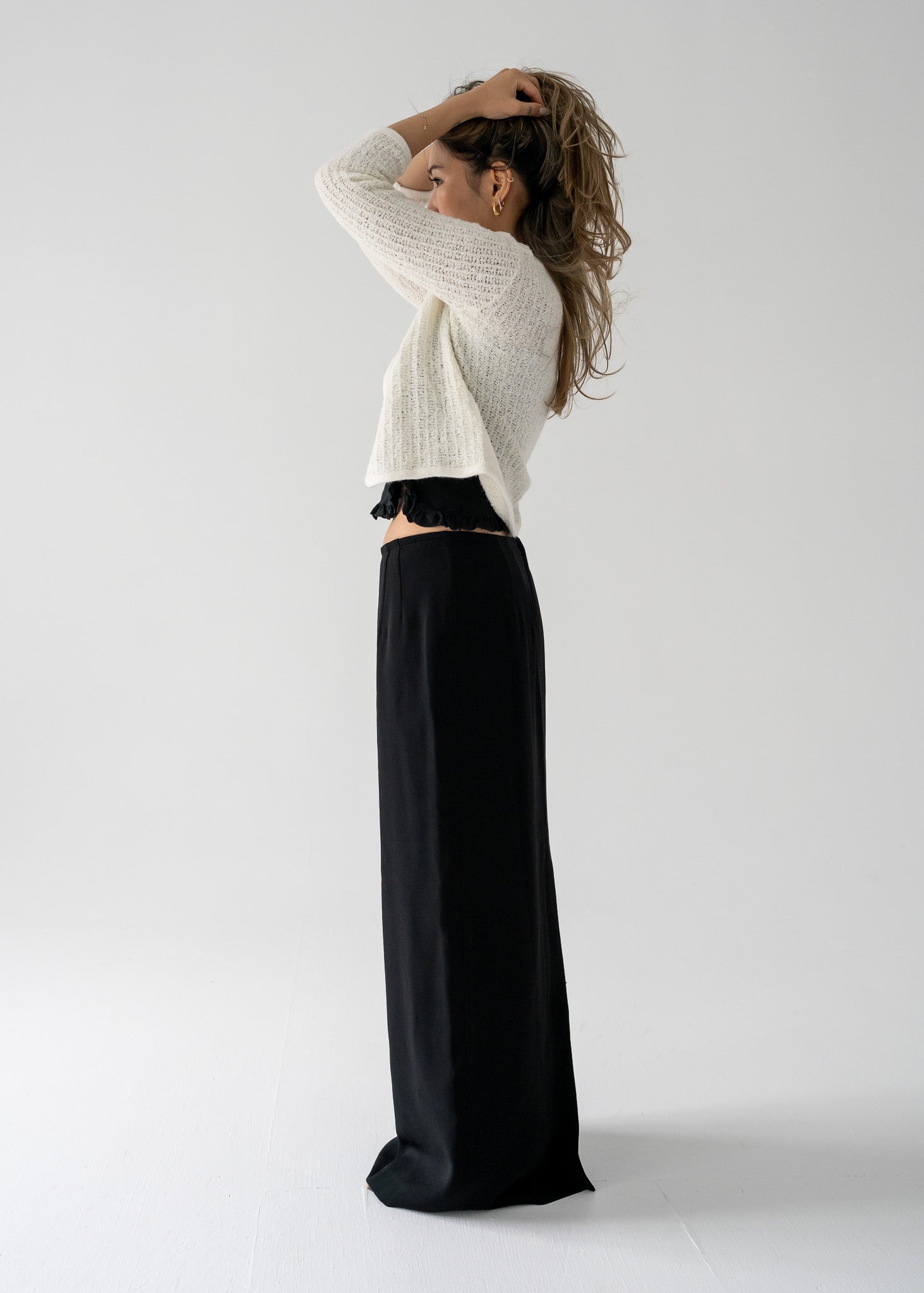 Person wearing a white sweater and vintage black column skirt against a plain background