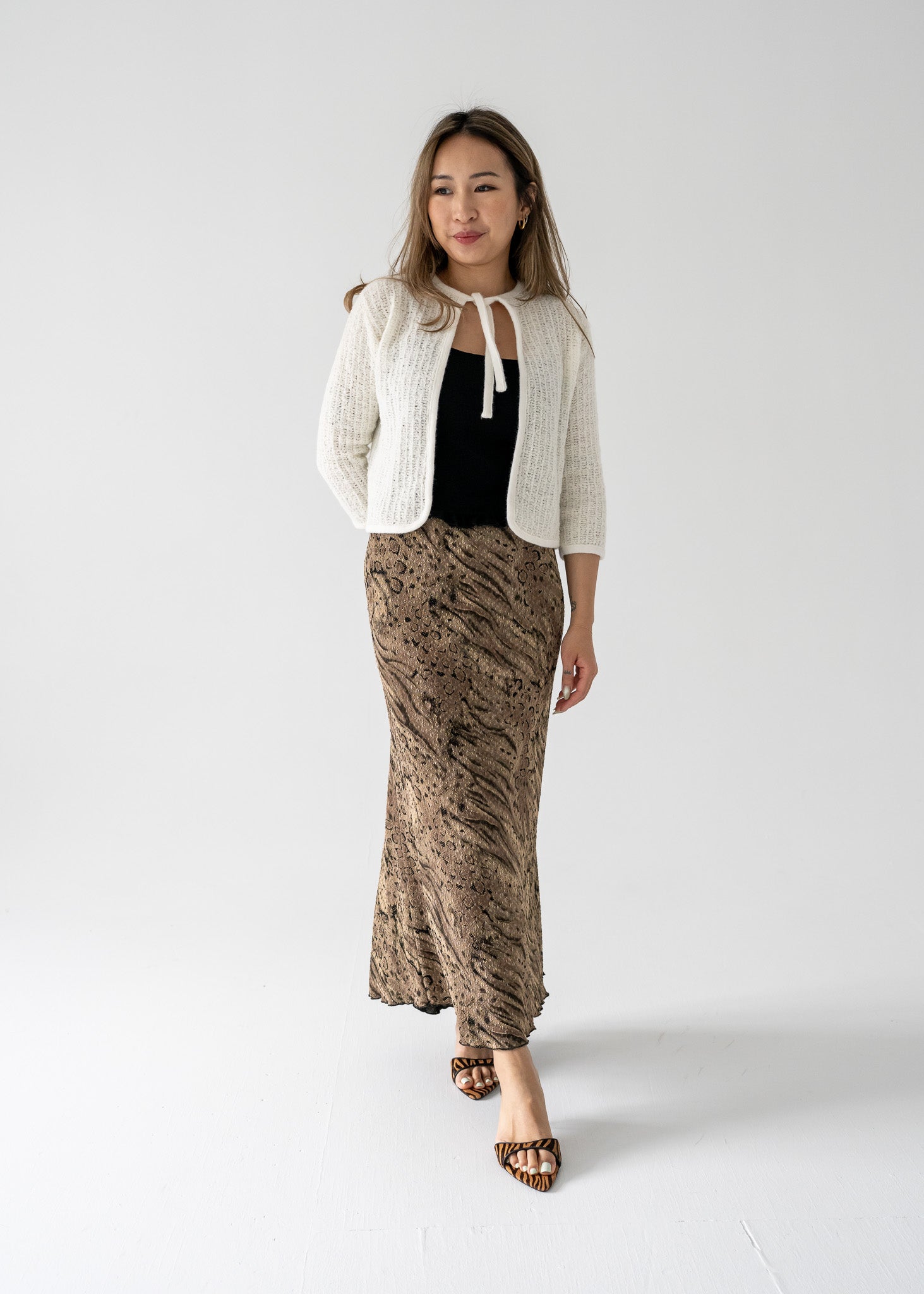 A model wearing a vintage long maxi skirt with a bronze and black abstract animal print, paired with a white top and accessories.