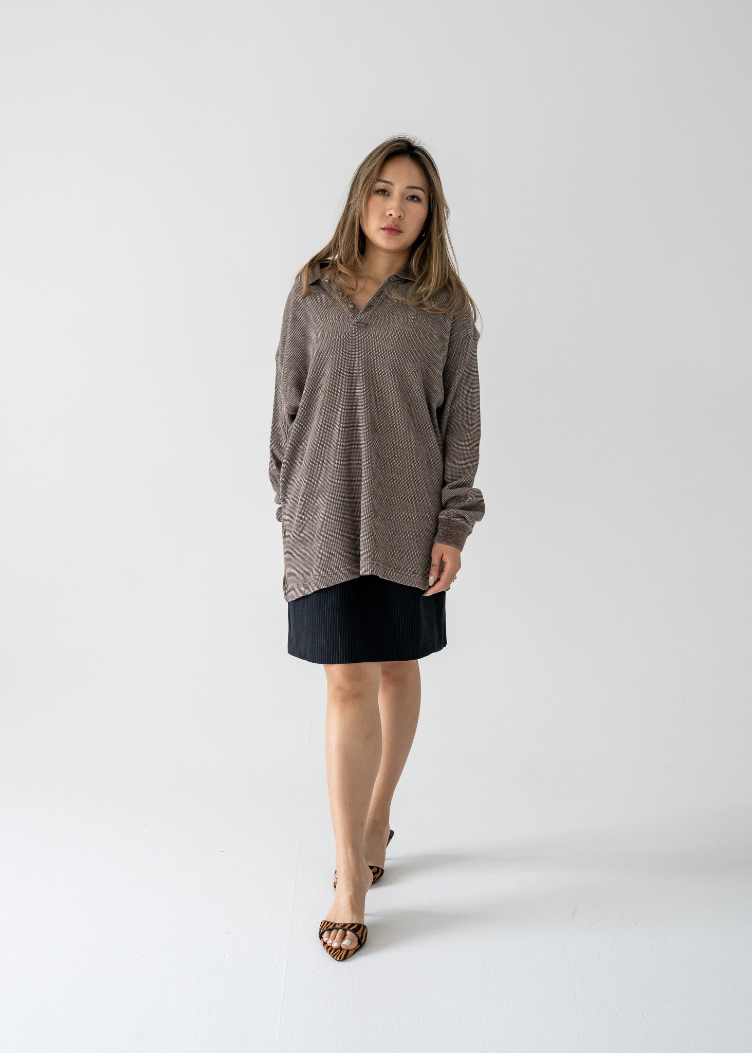 Woman wearing a vintage brown long-sleeve top and black skirt on a white background