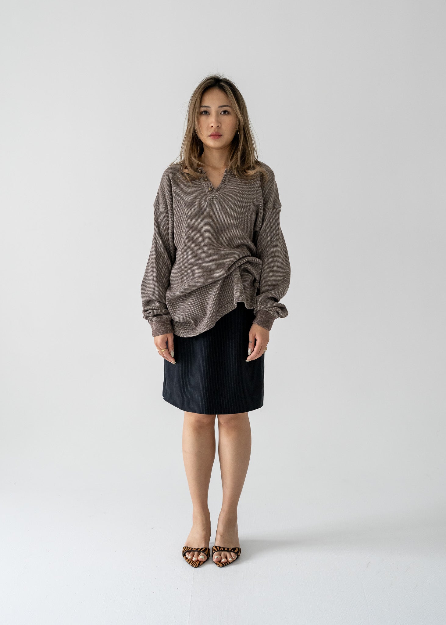A person standing wearing a vintage brown long sleeve collared waffle knit shirt and a black skirt.