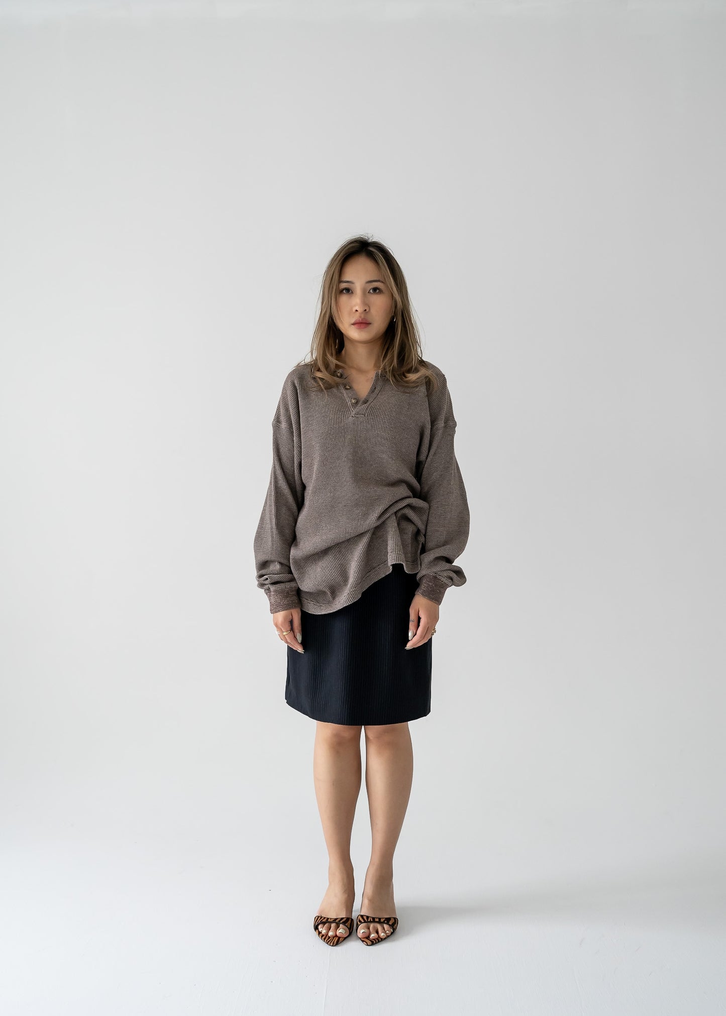 Woman wearing a brown sweater and vintage fitted A-line mini skirt in black and white stripes on a white background