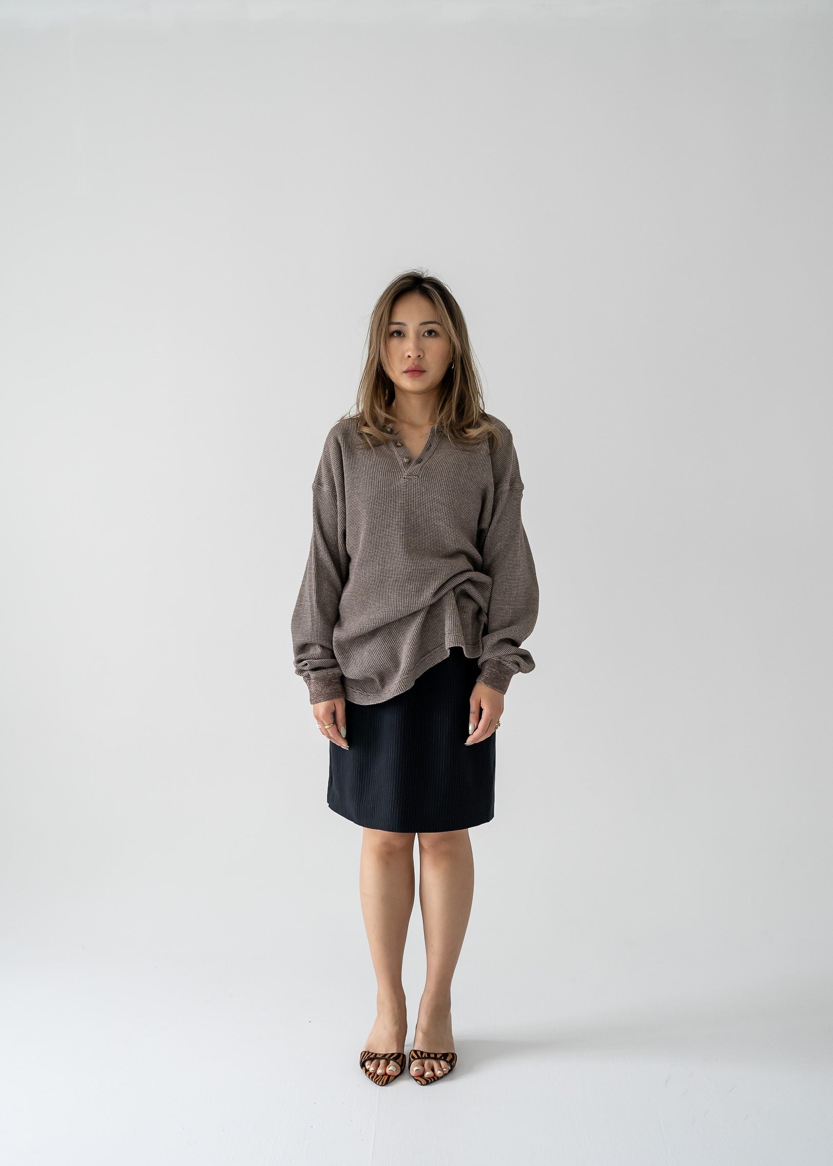 Woman wearing a brown sweater and vintage fitted A-line mini skirt in black and white stripes on a white background