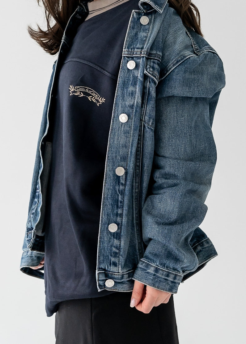 Person wearing a vintage denim jacket over a black shirt on a plain background