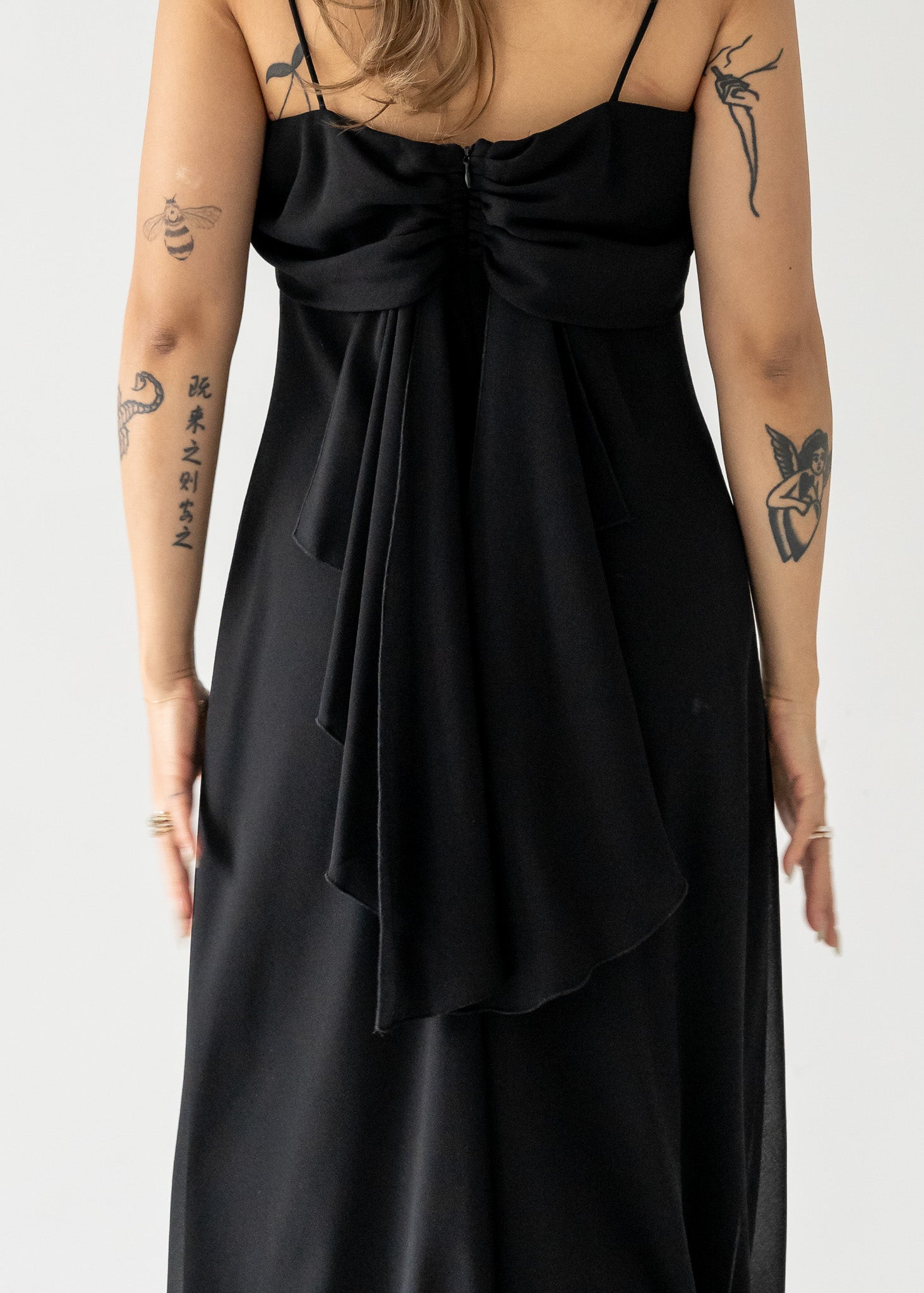 Vintage black dress with a tie detail on a plain background