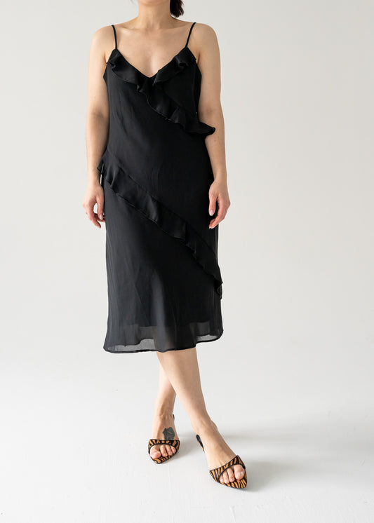 A model wearing a vintage black spaghetti strap bias ruffle midi dress with a V-neck and flat hem.