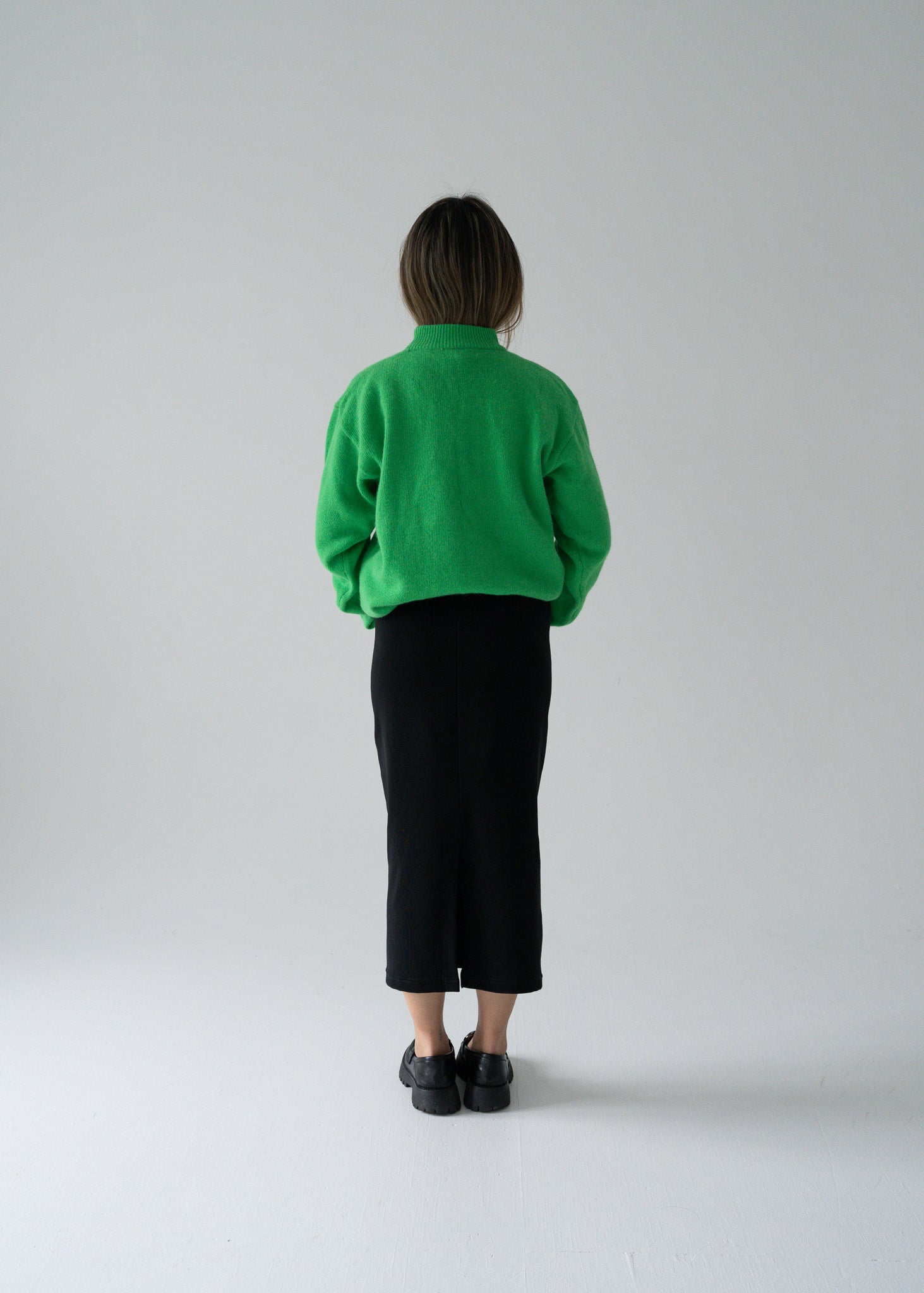 Person wearing a green angora sweater and vintage black skirt against a plain background