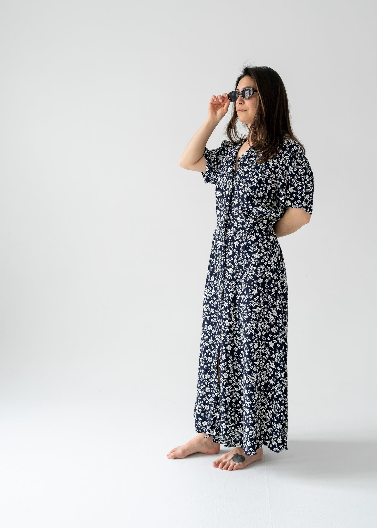 Woman in a vintage navy and white cherry blossom print button-up short sleeve maxi dress posing against a plain background