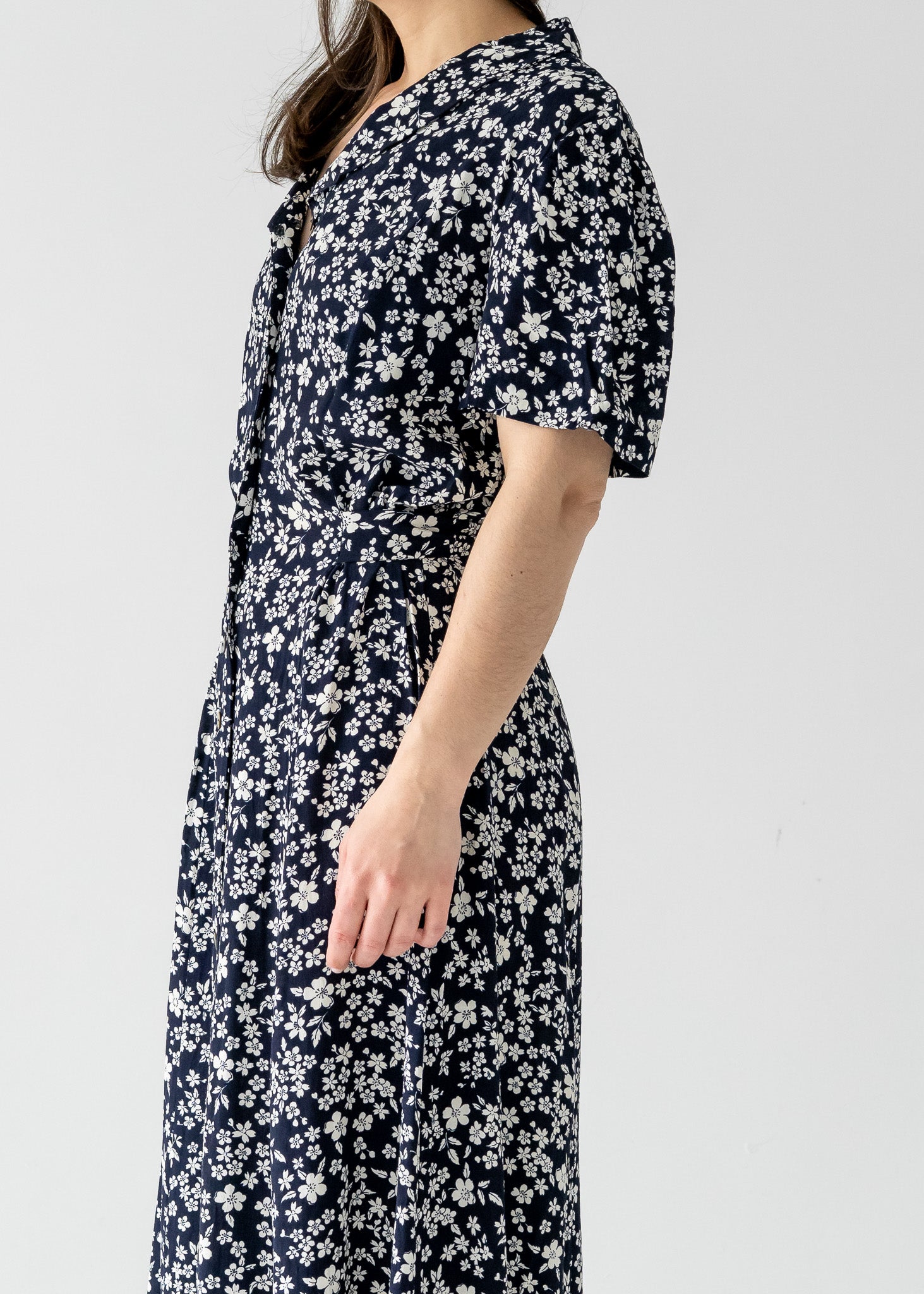 Person wearing a vintage navy and white cherry blossom print button-up short sleeve maxi dress on a plain background