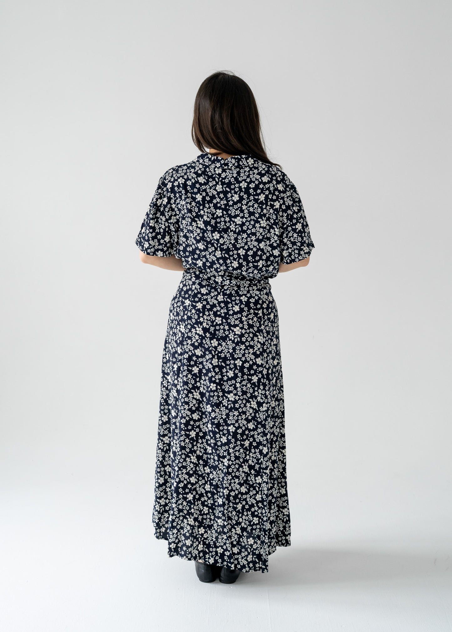 Woman wearing a vintage navy and white cherry blossom print button-up short sleeve maxi dress on a white background
