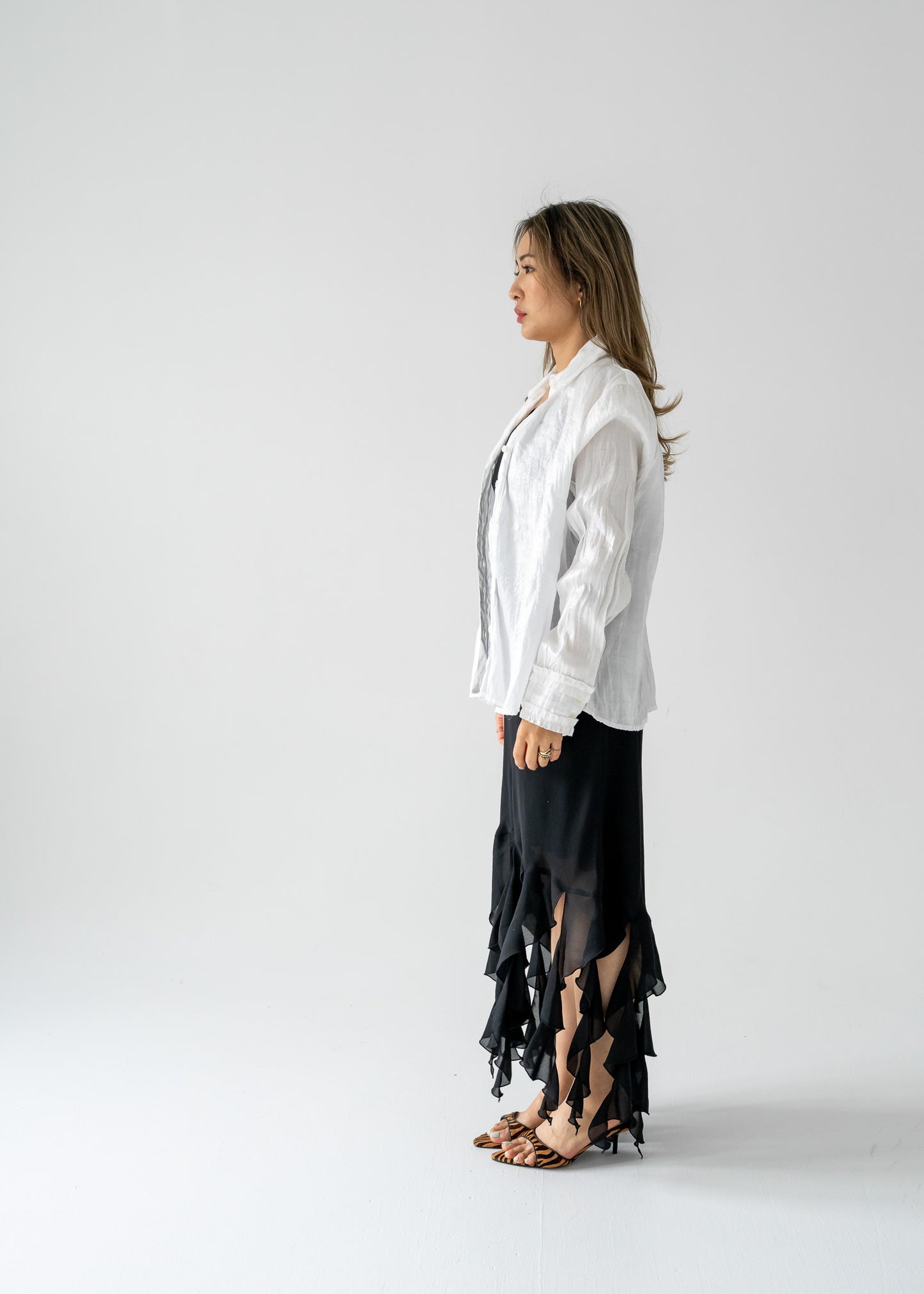 Woman in white shirt and black vintage ruffled dress on a light background