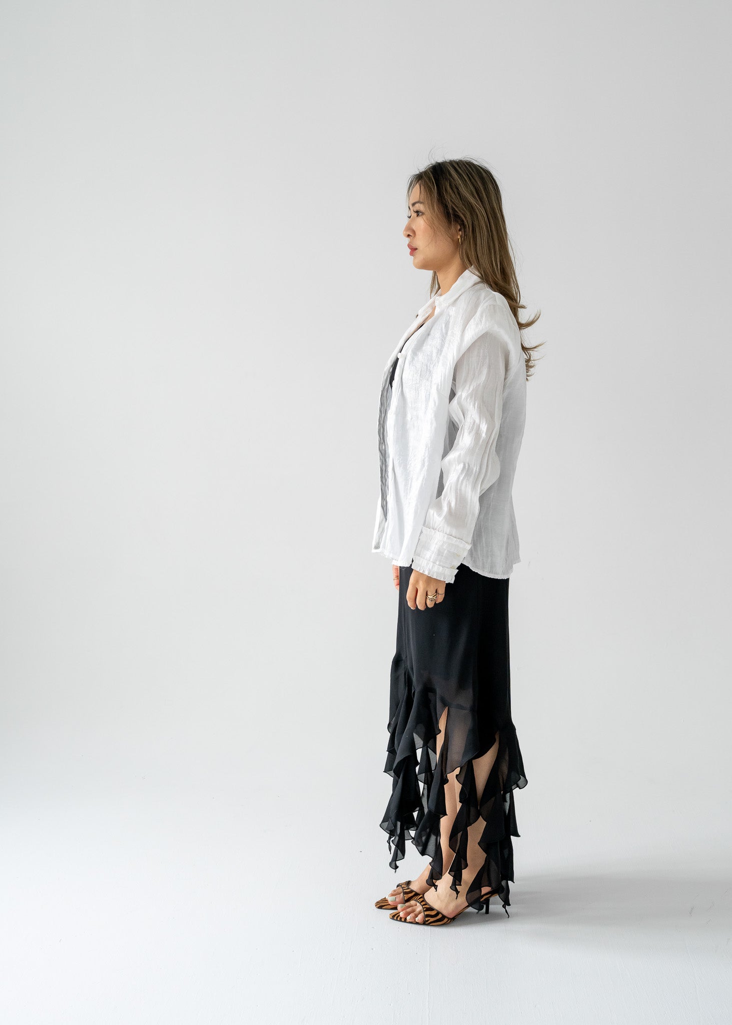 Woman in white shirt and black vintage ruffled dress on a light background