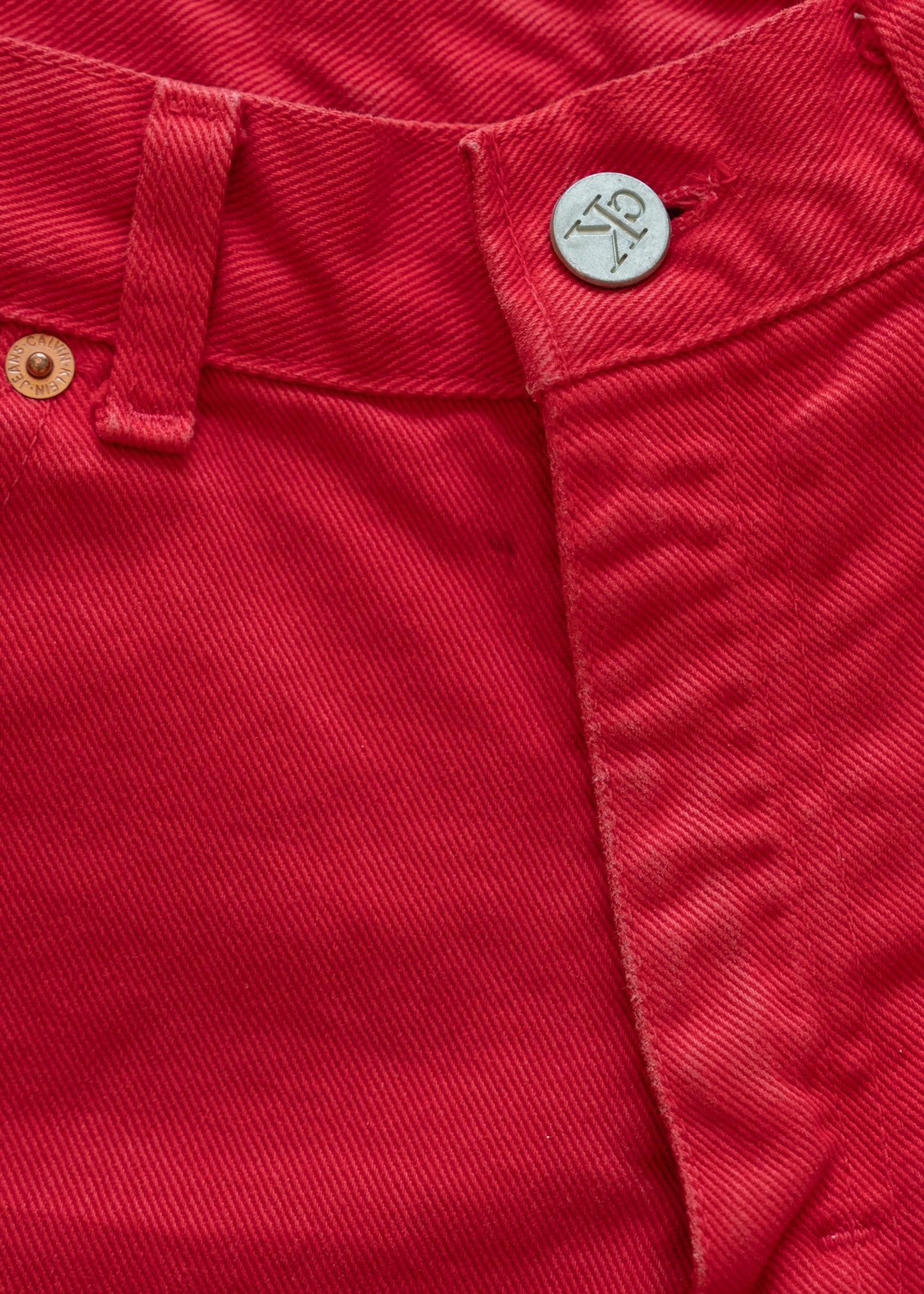Close-up of denim red shorts with a button and stitching detail