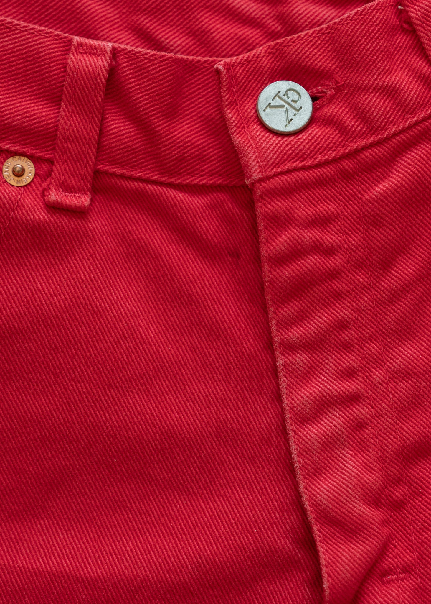 Close-up of denim red shorts with a button and stitching detail