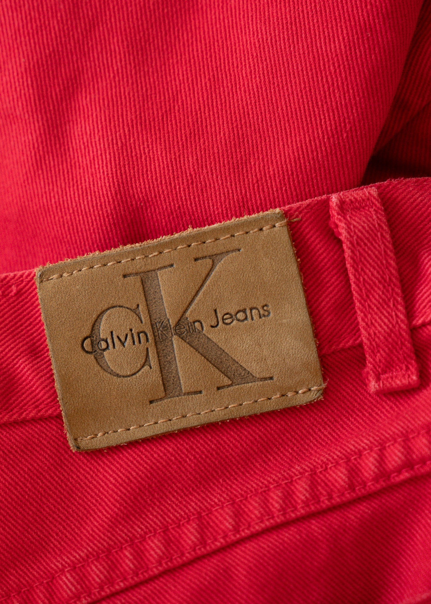 Calvin Klein Jeans label on a red denim fabric background