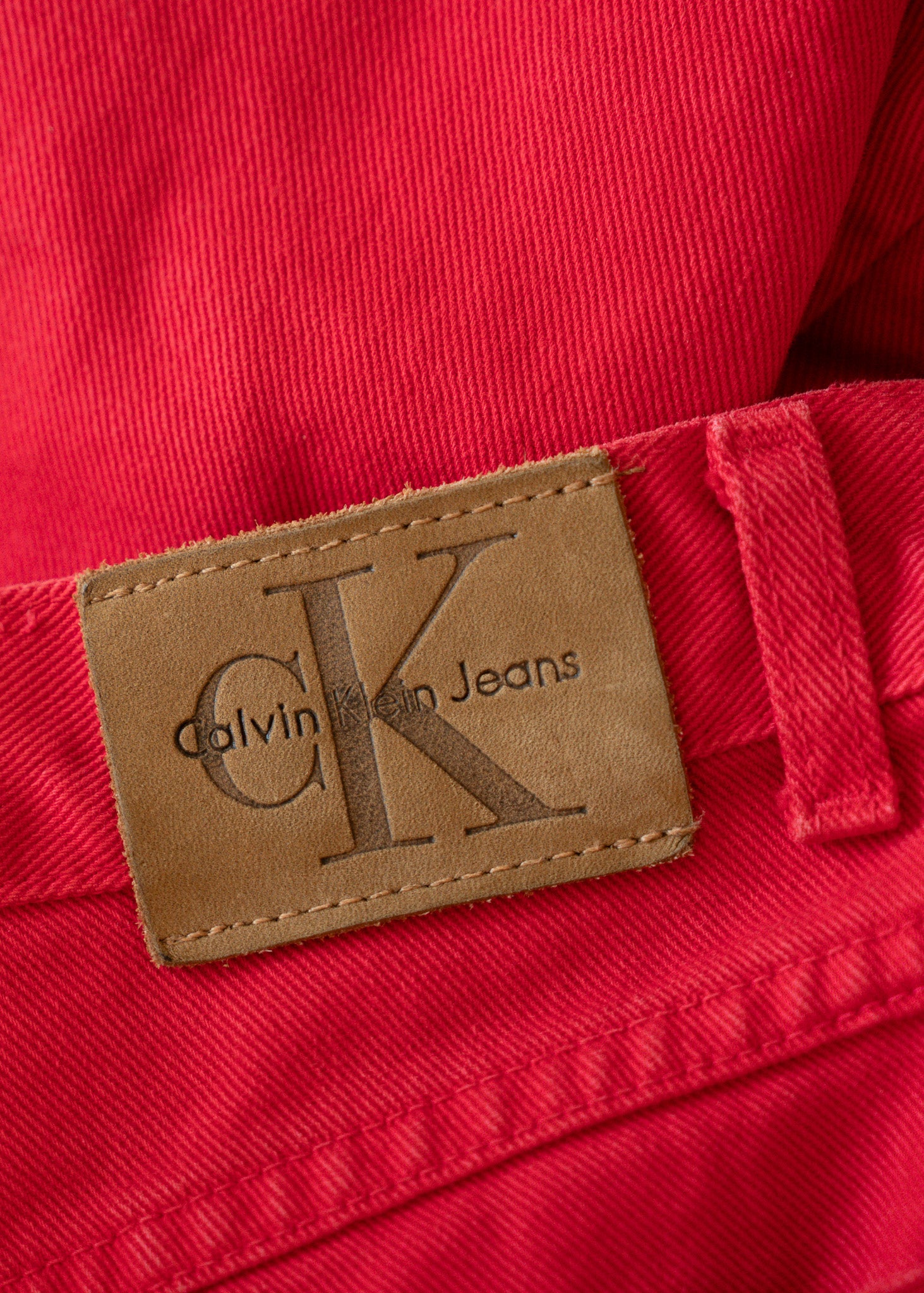 Calvin Klein Jeans label on a red denim fabric background