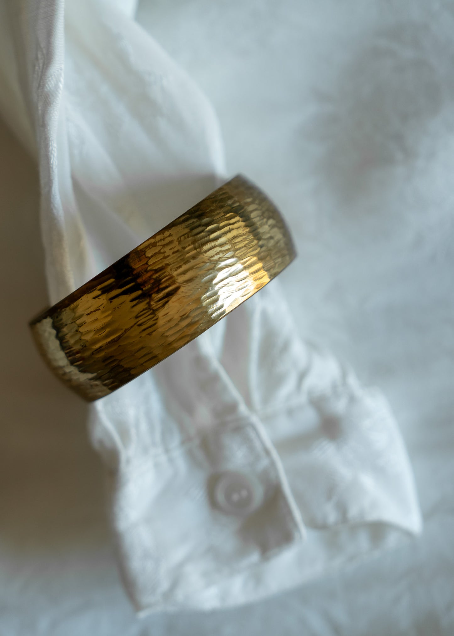 Etched brass bangle on a white fabric background