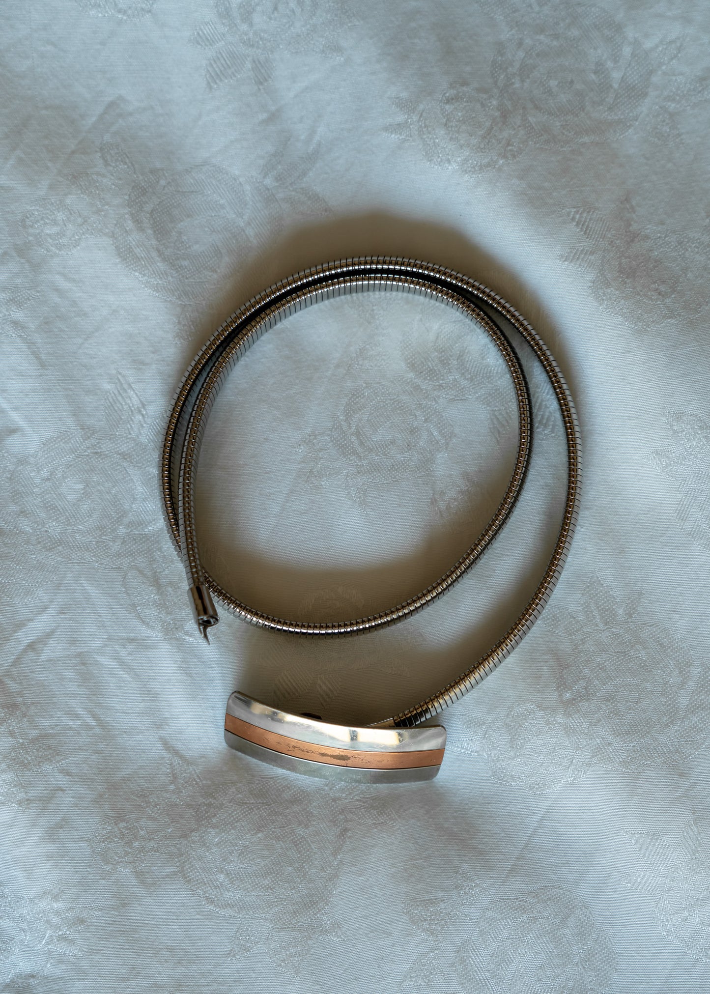 Silver metal belt on a textured white surface