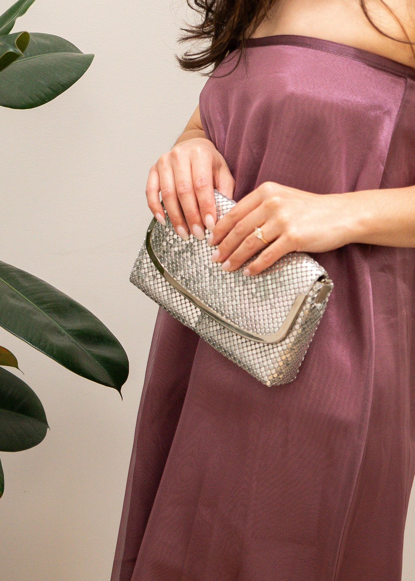 Person holding a silver clutch with a neutral background