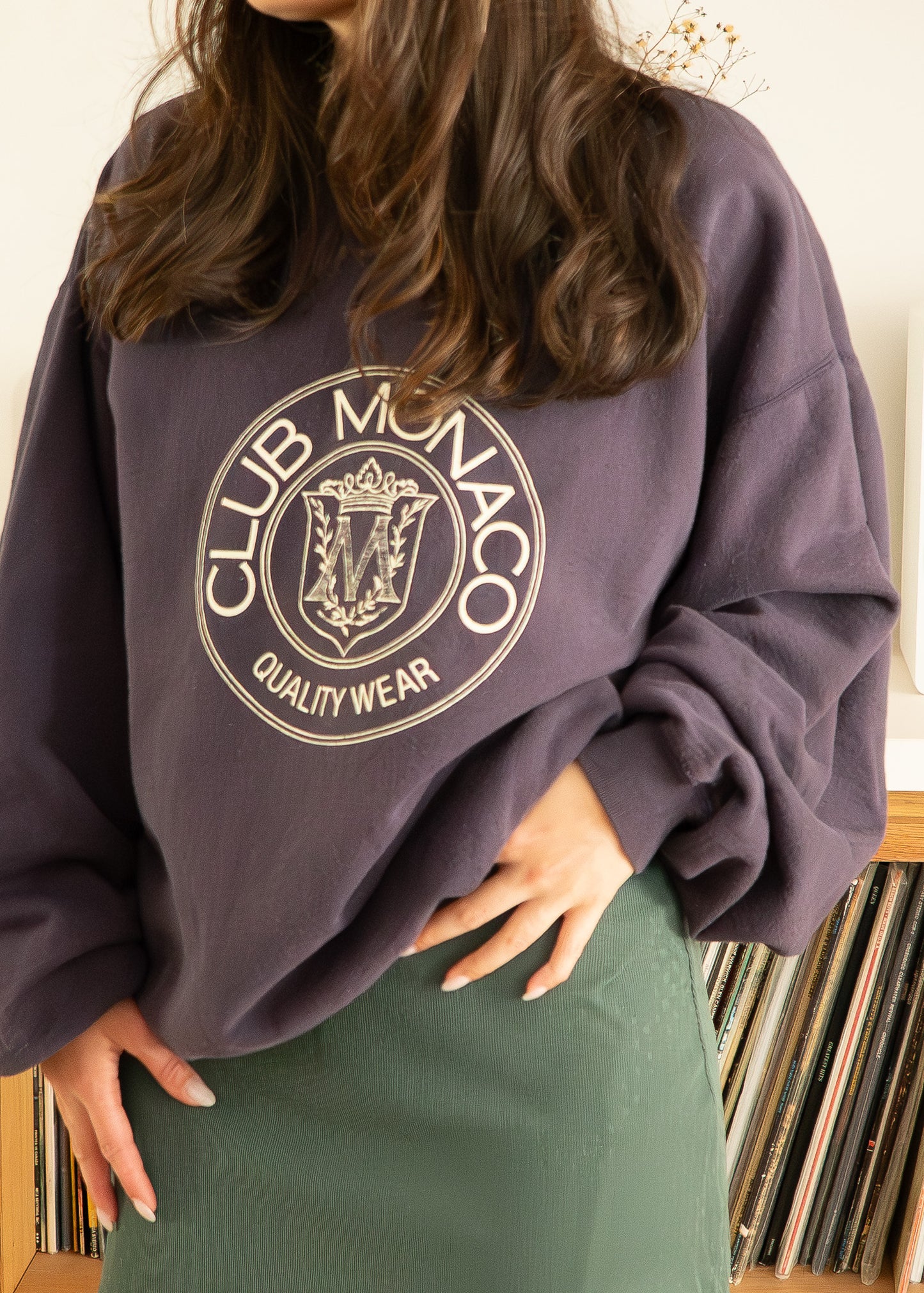 Person wearing a vintage purple Club Monaco sweatshirt with a record collection in the background