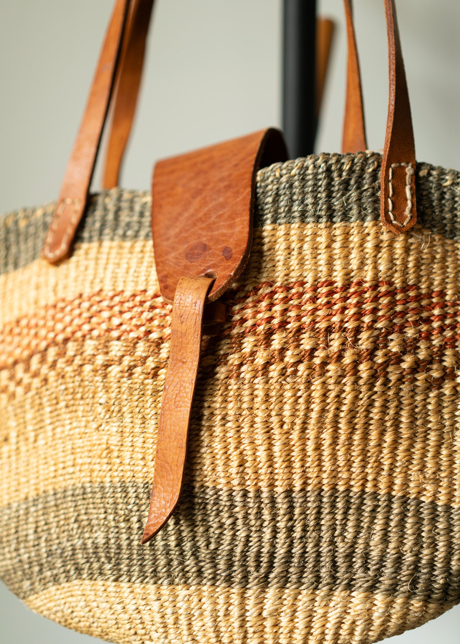 vintage woven bag with leather straps on a neutral background